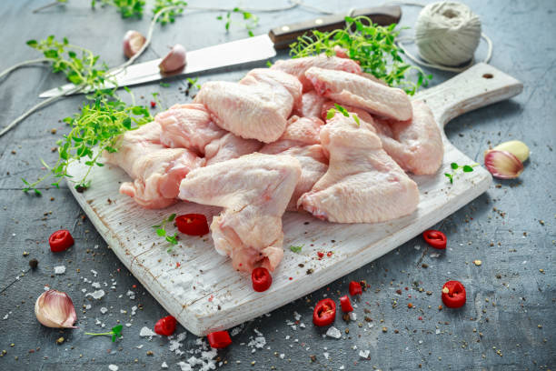 istock Fresh raw chicken wings on a white cutting board with thyme, chilli, salt, pepper, garlic 824660362