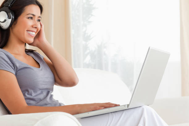 istock happy woman sitting on sofa with notebook and earphones 824663104