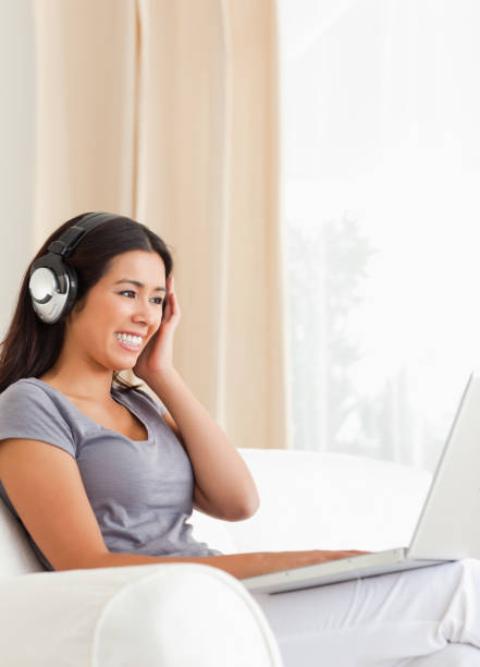 istock smiling woman sitting on sofa with notebook and earphones 824663128