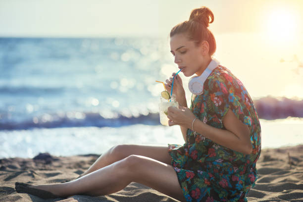 istock Young woman drinking cocktail on the beach 824676980