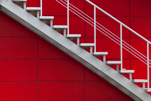 gray metal stair on the red wall. minimalism concept.