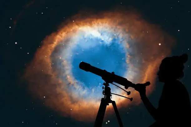 Girl looking at the stars with telescope. The Helix Nebula or NGC 7293 in the constellation Aquarius. 