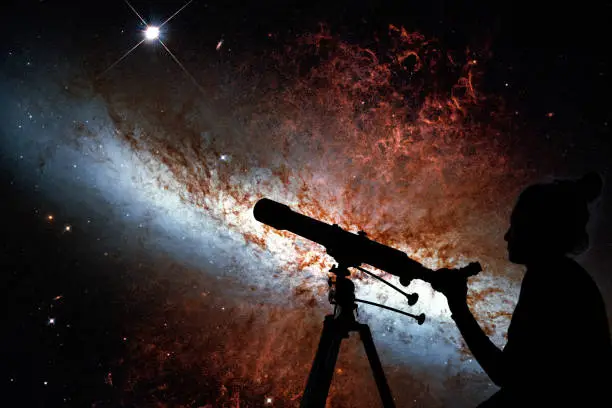 Girl looking at the stars with telescope. Messier 82, Cigar Galaxy or M82 in the constellation Ursa Major