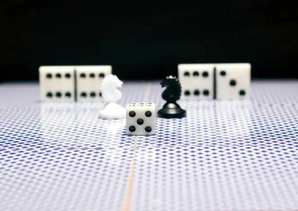 Photo of Chess dice and dominoes on a reflective surface
