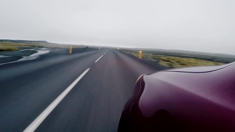 Close-up view of the front fender of red car going through the countryside road. Vehicle traveling on high speed