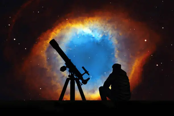 Man with telescope looking at the stars. The Helix Nebula or NGC 7293 in the constellation Aquarius. 