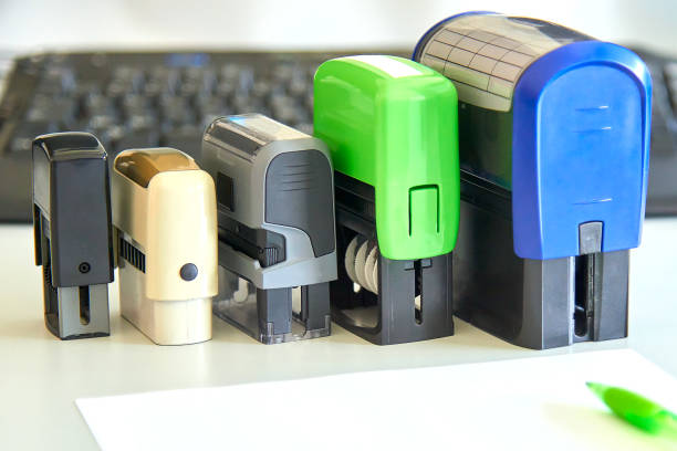 Five handle automatic stamps, sheet of paper and pen on a desk