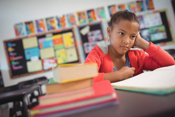 istock Thoughtful schoolgirl sitting at desk 824709984