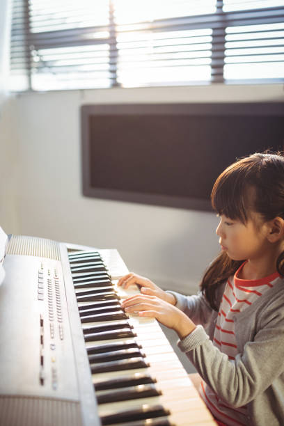 istock High angle view of concentrated girl practicing piano in class 824710150