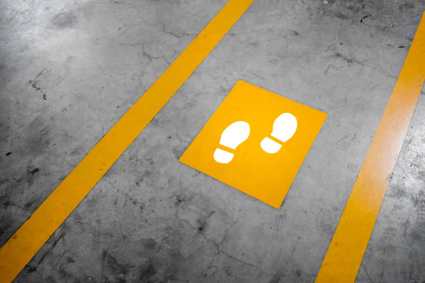 Walkway lane in parking building. Painted yellow footsteps between parallel yellow lines on abstract cement floor. Step by step concept.