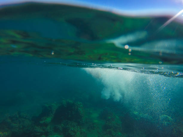 istock Underwater landscape with natural water split, blue sky above and green water below. 824713872