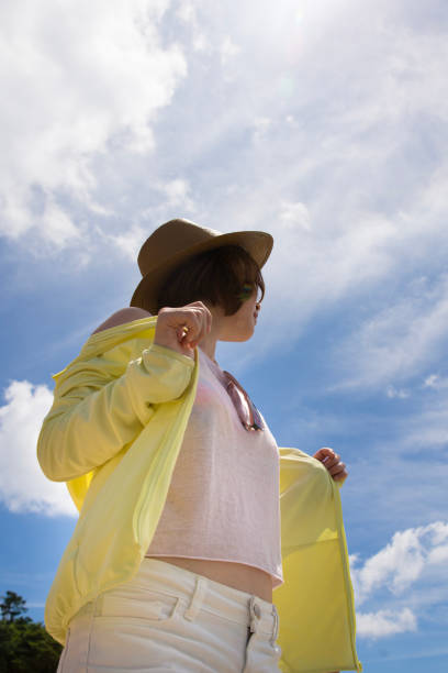 istock Young woman standing on bearch, looking up the sky 824727298