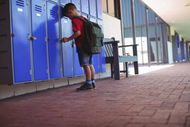 istock Full length of boy leaning on lockers in corridor 824730212