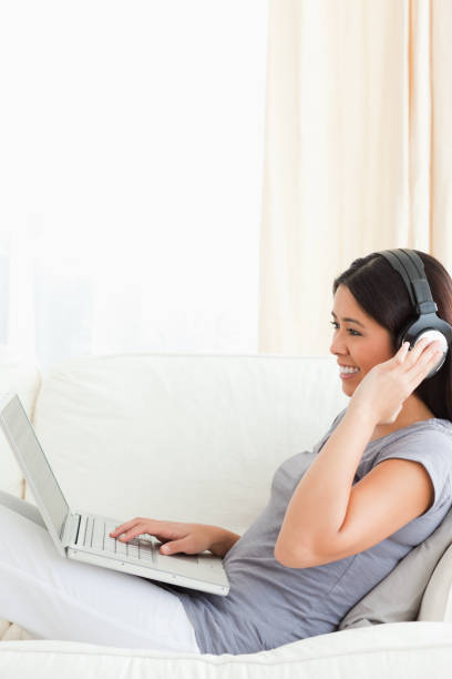 istock young woman with earphones on sitting on sofa 824730380