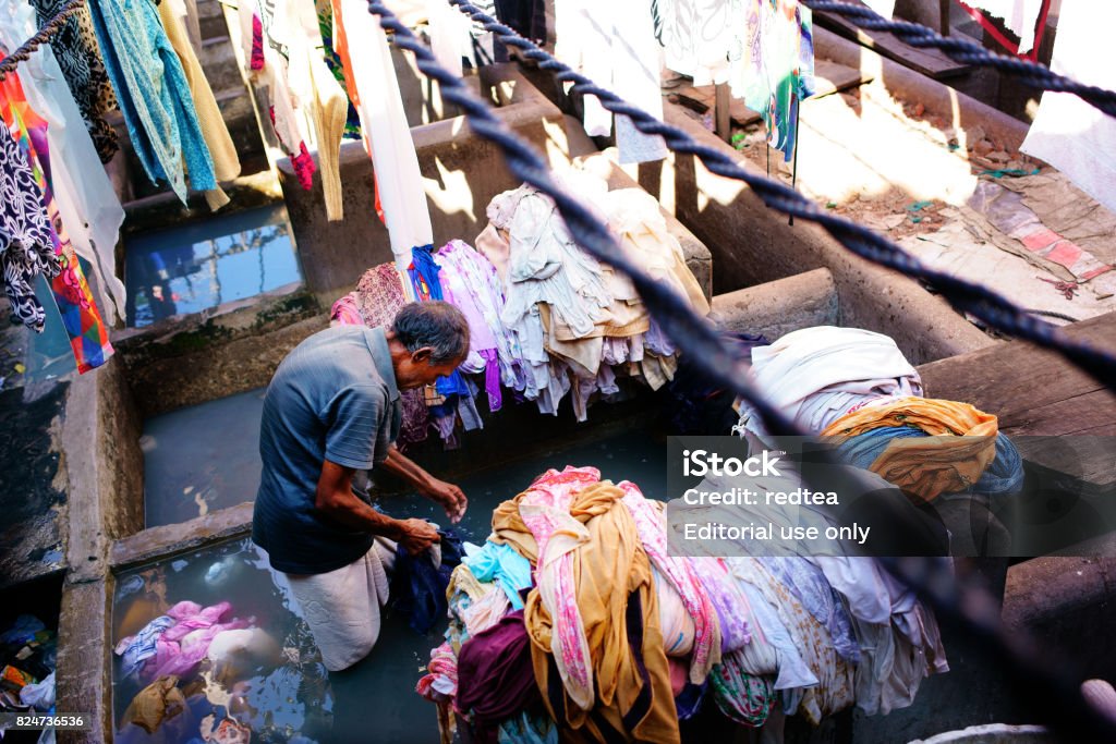 Indian workers washing clothes at Dhobi Ghat in Mumbai, India Mumbai, India - January 27, 2017: Mumbai, India - January 12, 2016: Indian workers washing clothes at Dhobi Ghat, a well know open air laundromat in downtown of Mumbai, Maharashtra State。 Adult Stock Photo