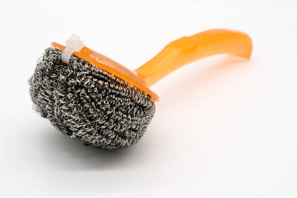 New wire steel wool scourer with orange plastic handle for pan and pot scrubber isolated on white background. Abrasive surface sponge equipment for heavy cleaning.