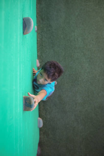istock Boy reaching climbing holds on green wall 824740882