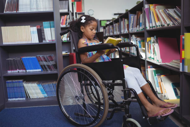 istock Girl reading book on wheelchair in library 824740984