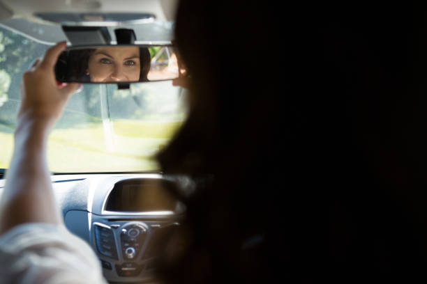 istock Woman looking into rear view mirror while driving a car 824744288