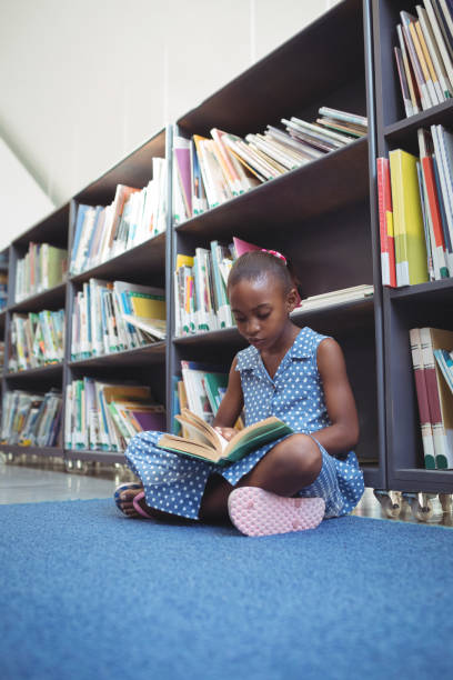 istock Girl reading book while sitting in library 824750468
