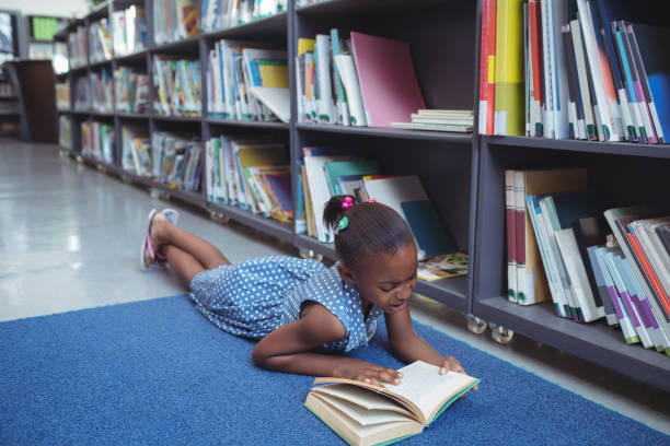 istock Girl reading book by shelf in library 824750486