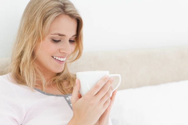 istock Woman looking into the cup in her hands and smiling 824760104