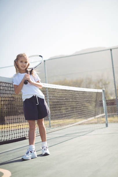 istock Girl holding tennis racket while sitting by net 824762826