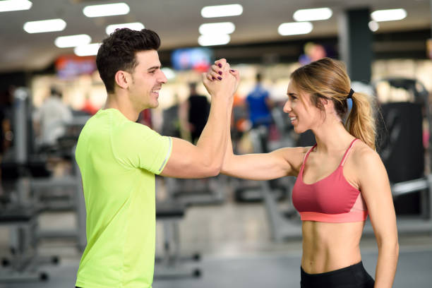 istock Smiling young man and woman doing high five in gym 824765996
