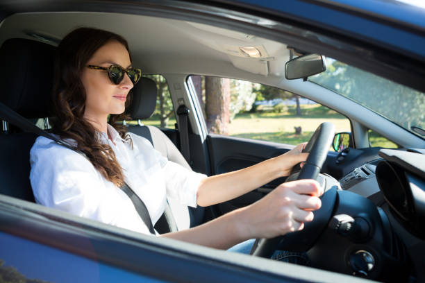 istock Senior woman looking into rear view mirror while driving a car 824767128