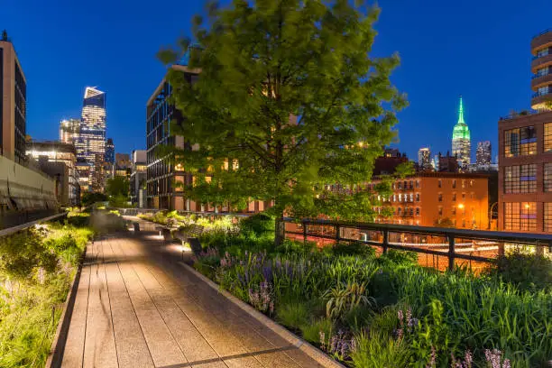 High Line promenade at twilight with city lights and illuminated skyscrapers. Chelsea, Manhattan, New York City