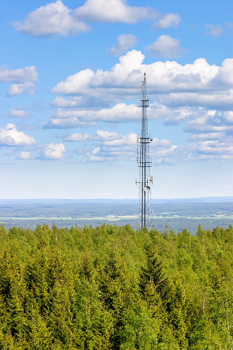 Communication mast in a forest and with aerial view of the landscape