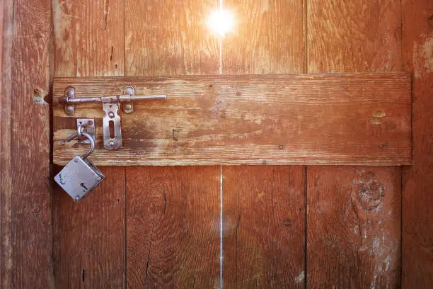 old wooden door with metal knob and master Key with sun ray came throught doorl hole