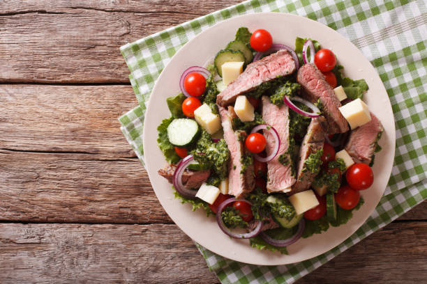 istock Salad with beef steak, cheese and vegetables dressed with chimichurri sauce. horizontal top view 824788348