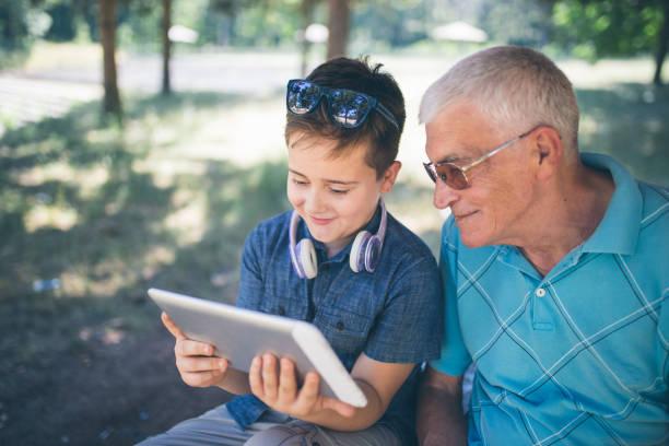 istock Grandfather and grandson using tablet in the city park 824788884