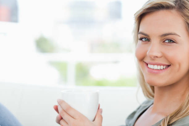 istock Woman smiling, looking forward and holding up a mug in hands 824792756