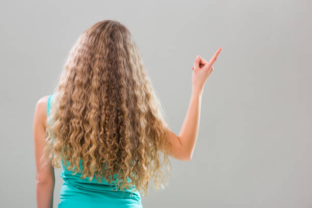 Woman with gorgeous long blonde hair gesturing on gray background.