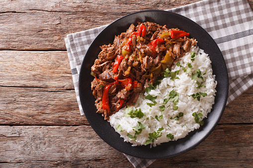 ropa vieja: beef stew in tomato sauce with vegetables and rice garnish on a plate close-up. horizontal view from above