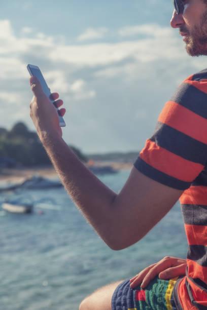 istock Young man using cellphone / smartphone near ocean. 824797722
