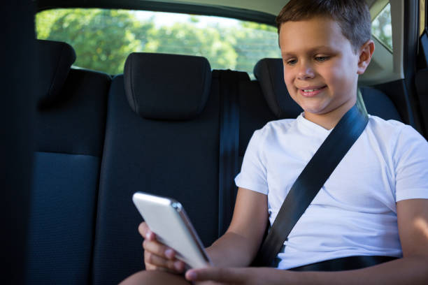 adolescente, usando telefone celular no banco de trás do carro - mobile phone seat belt text messaging smiling - fotografias e filmes do acervo