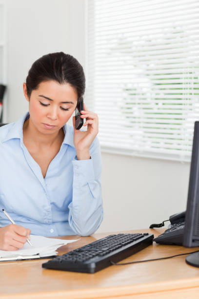 istock Lovely woman using her mobile phone while writing on a sheet of paper 824801090