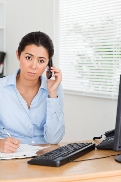 istock Beautiful woman using her mobile phone while writing on a sheet of paper 824801290