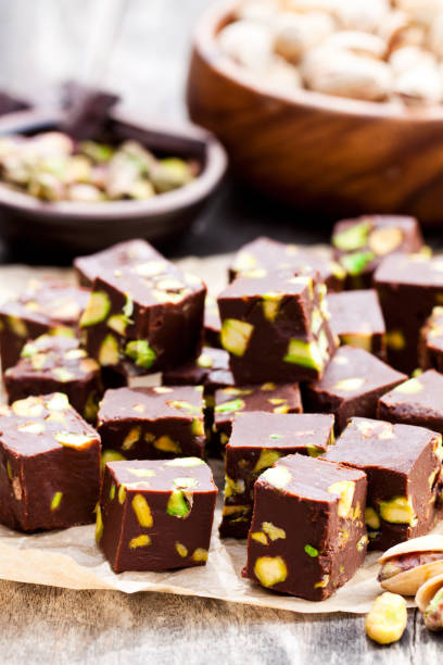 istock Dark  chocolate cubes with pistachios on wooden background 824815992