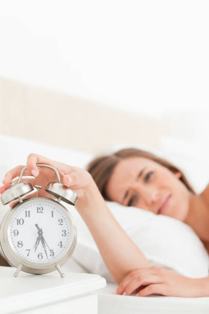 istock Woman silencing her alarm clock with her hand 824819990