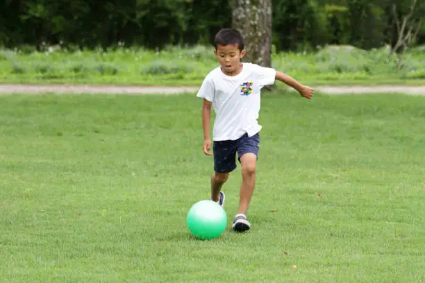 Photo of Japanese boy playing with soccer ball (second grade at elementary school)