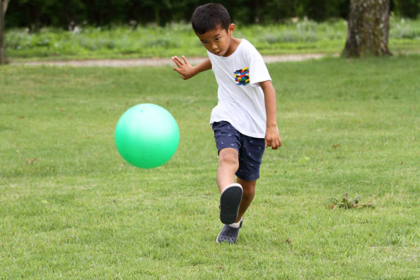 Japanese boy playing with soccer ball (second grade at elementary school)