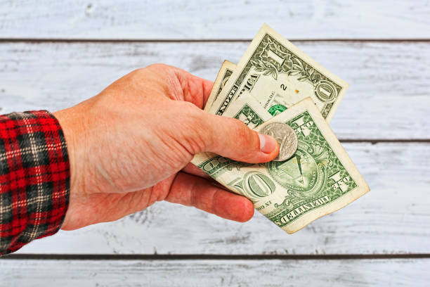 istock A few US dollars holded in man hamd dressed in work checkered shirt 824827684