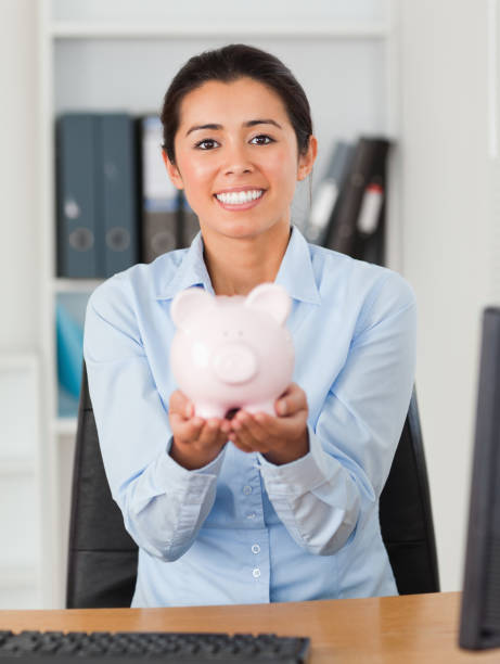istock Good looking woman holding a piggy bank while looking at the camera 824831772