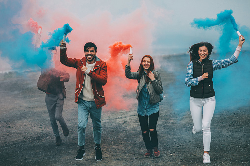 Friends running with smoke bombs in their hands.