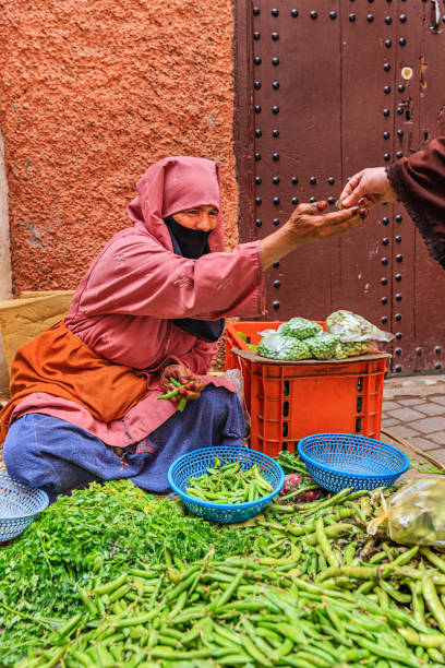 Morrocan woman selling vegetables on street market, Marrakech Morrocan woman selling vegetables on street market near Djemaa el Fna square, Marrakech, Morocco. Djemaa el Fna is a heart of Marrakesh's medina quarter. moroccan woman stock pictures, royalty-free photos & images