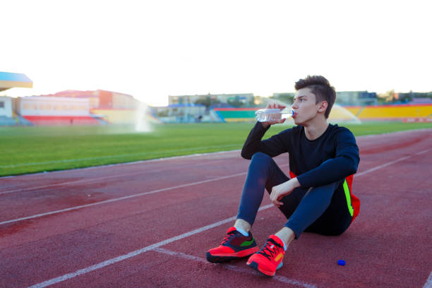 Athlete drinks water at the stadium - fotografia de stock